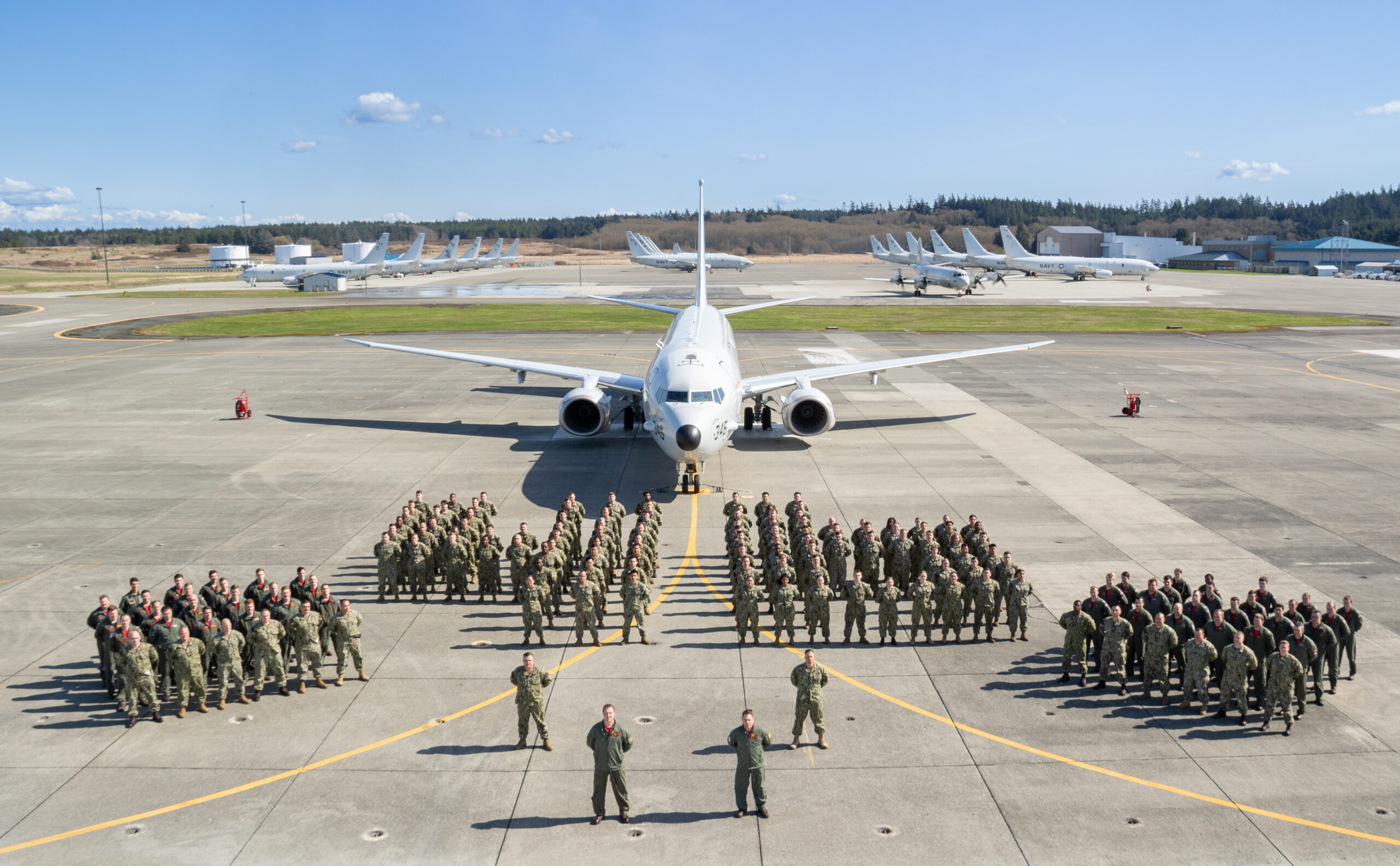 NAVAL AIR STATION WHIDBEY ISLAND, Wash. (April 14, 2023) -- Sailors attached to Patrol Squadron (VP) 46, the "Grey Knights," stand arranged in a "46" formation in front of a P-8A Poseidon for a command photo on the flight line at Naval Air Station (NAS) Whidbey Island, Wash., April 24, 2023.  Cmdr. Frank P. Verducci III, Commanding Officer of VP-46, and Cmdr. Kevin Harrington, Executive Officer of VP-46, stand in the front with Command Master Chief Benjamin Faulise and Master Chief Aircraft Maintenanceman Matthew Allen.  A P-3 Orion can be spotted in the background amongst the line of P-8A Poseidon's.  (U.S. Navy photo by Mass Communication Specialist 3rd Class Jacquelin Frost.)